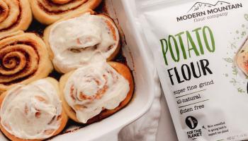 A pouch of Modern Mountain Potato Flour next to freshly iced cinnamon rolls