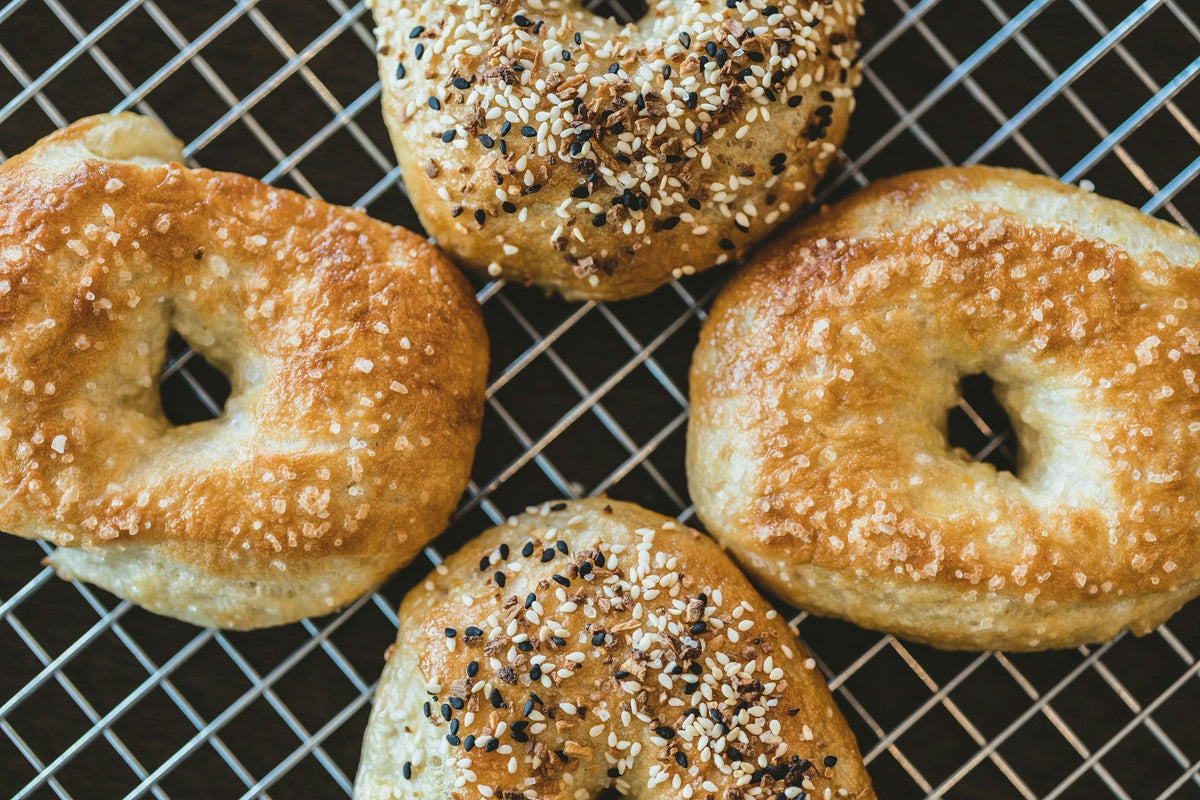 Golden sesame and everything bagels cooling on a wire rack
