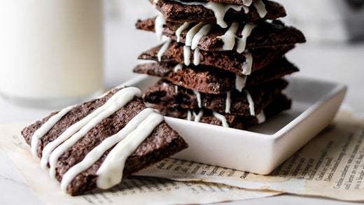 A stack of triple chocolate brownie brittle in front of a glass of milk